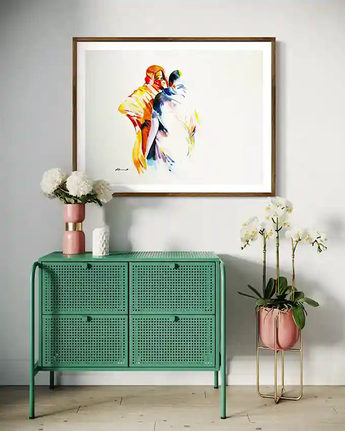 Green cabinet with decorative items and a colorful framed art print of Galal Yousif on a gray wall. Depicting 2 ladies. UAE