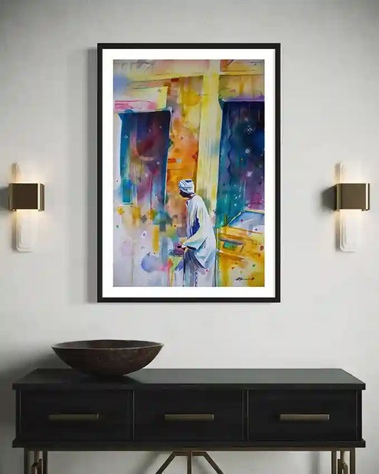 Colourful Framed print with a man by artist Galal Yousif on a wall above a black console table with a decorative bowl. UAE