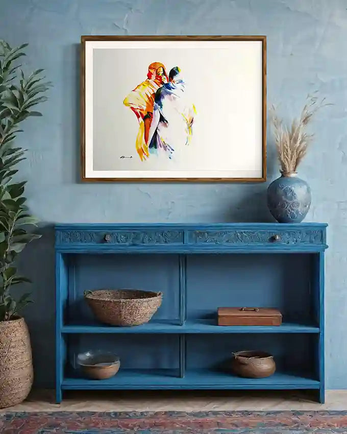 Framed abstract art print by Sudanese artist Glala Yousif above a blue shelf with decorative items against a blue wall. UAE