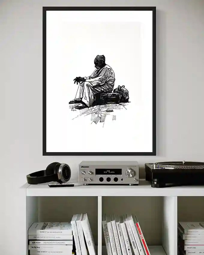 Framed "By the Roadside" black and white art print displayed above modern white shelf with audio equipment and books