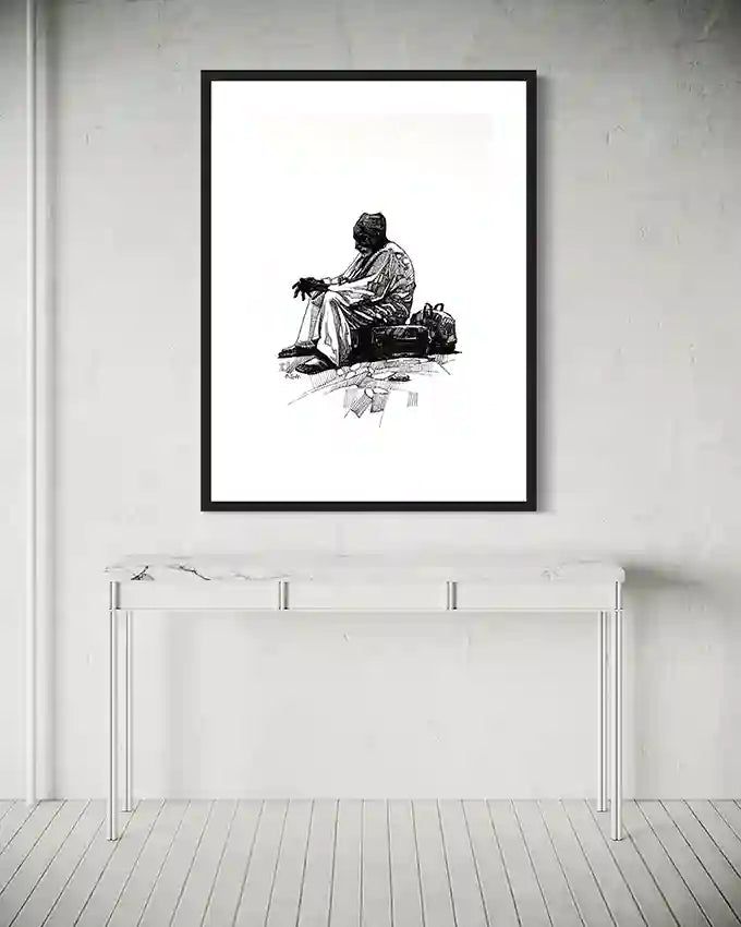 Framed "By the Roadside" art print hanging above modern glass console table in minimalist white room with wood floors