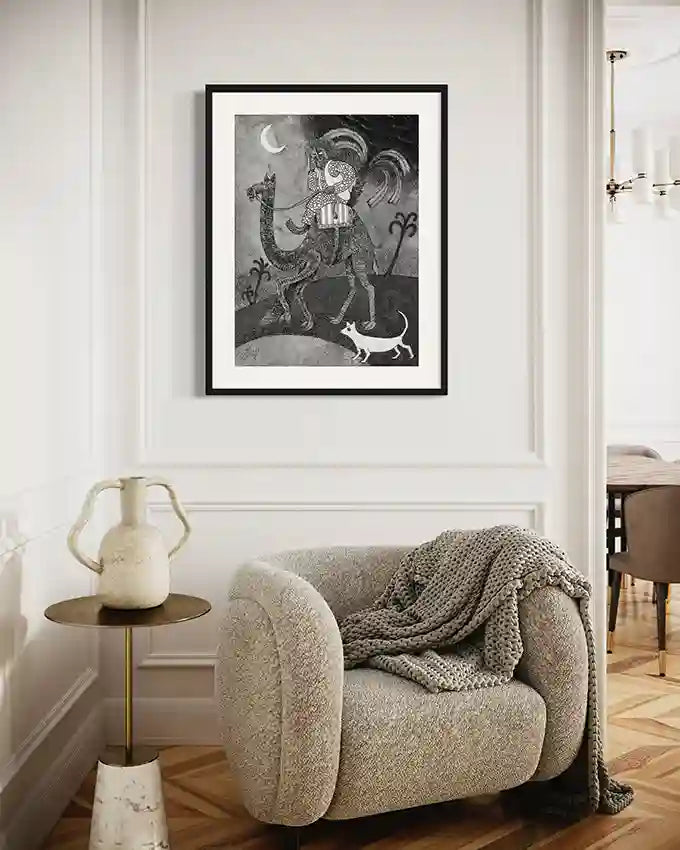 "The Midnight Traveler" art print displayed above beige armchair in elegant living room with side table and vase.