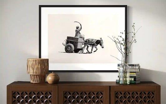 Echoes of the road art print by Obada Gabir displayed in black frame above wooden sideboard with decorative lamp and books in contemporary interior