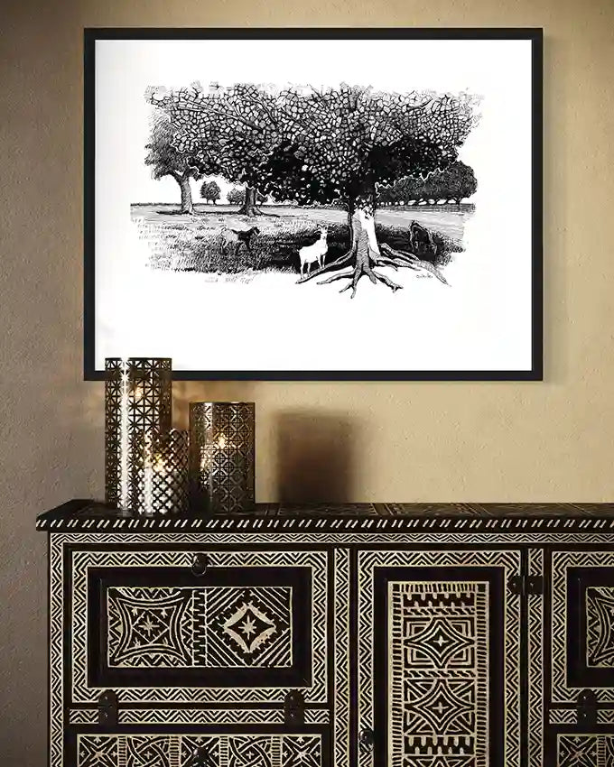 Pastoral Refuge black white art print by Obada Gabir in black frame above decorative wooden cabinet with geometric patterns
